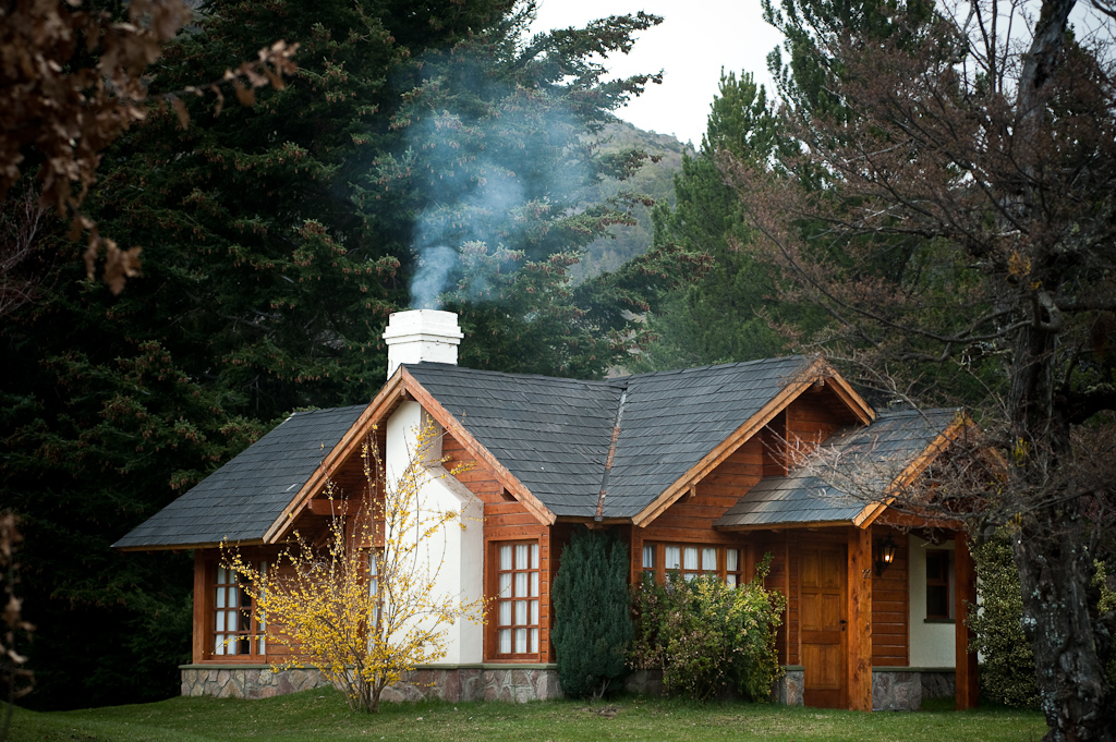 Timber and stone cabin at Parque Diana with smoke rising from the chimney