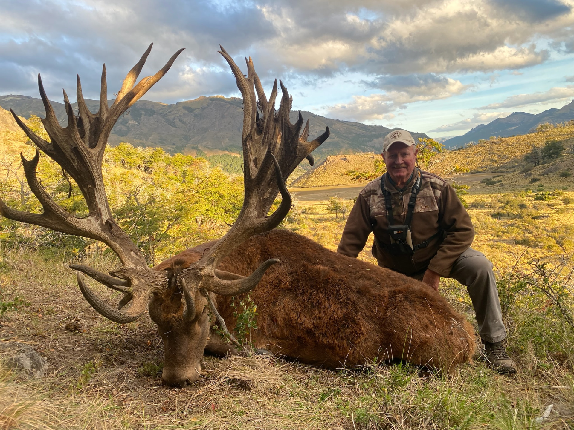 Hunter with a heavy-beamed red stag at sunset in the Andes