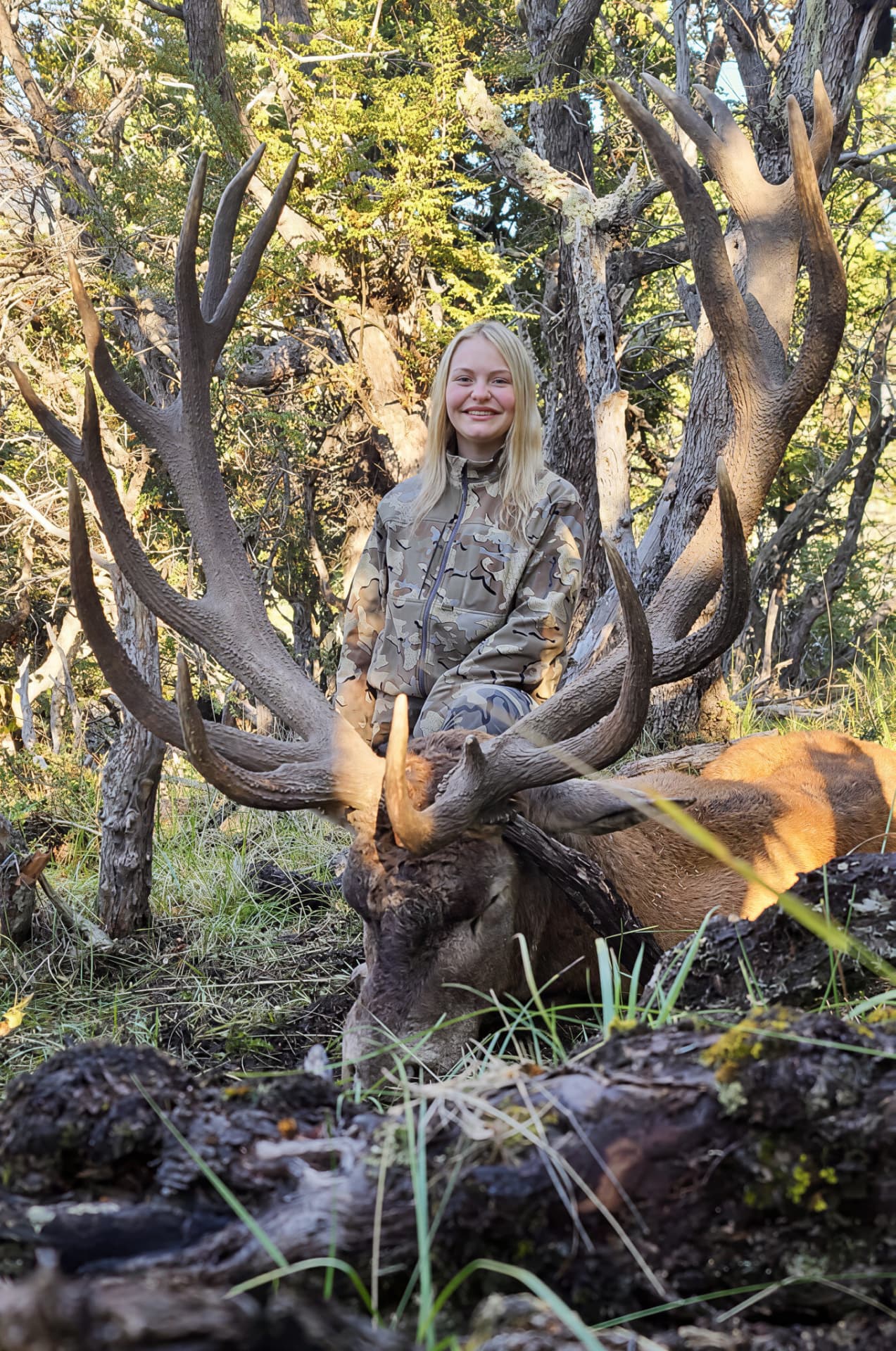 Young hunter with a heavy-antlered red stag in the forest