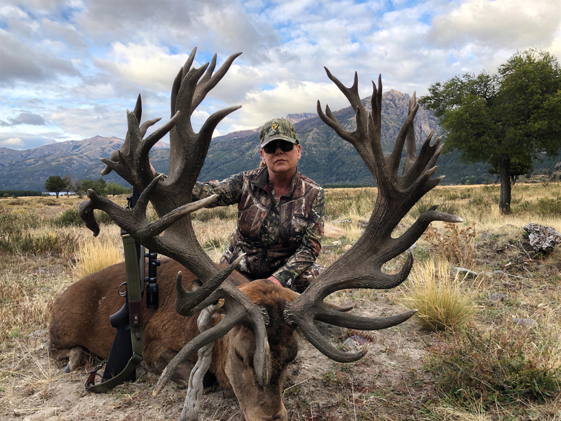 Lady hunter with a wide, heavy red stag on the valley flats