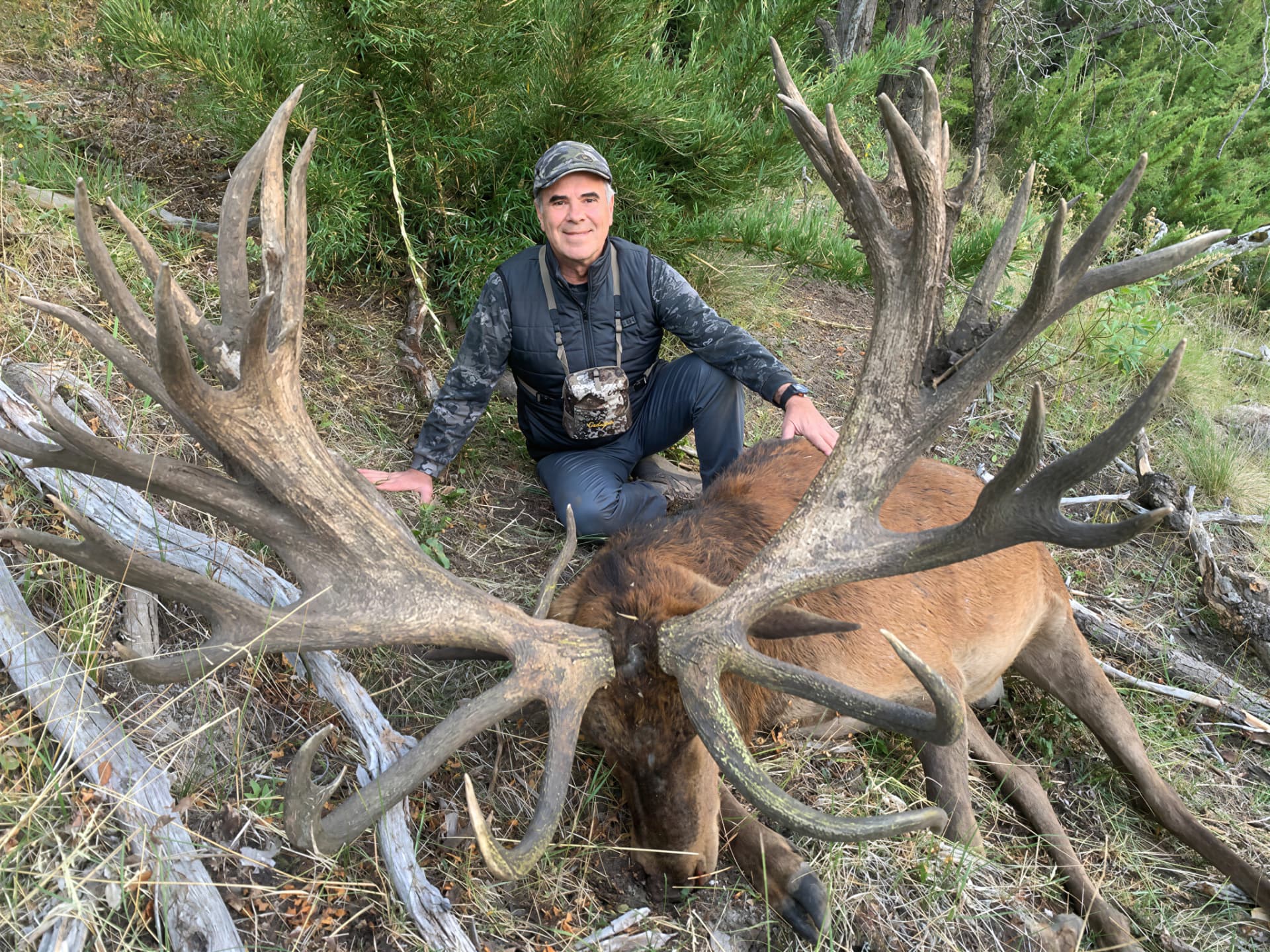 Hunter beside an enormous palmated red stag in the timber