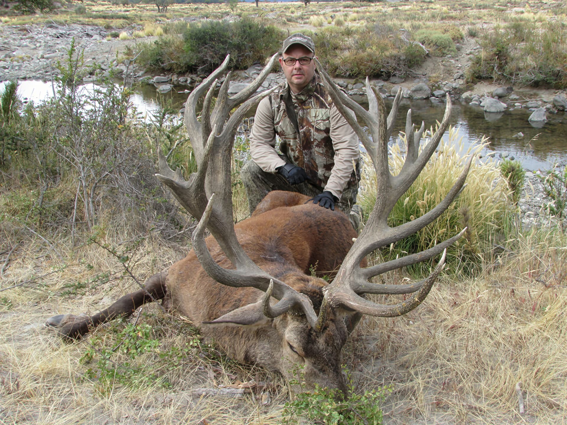 Hunter with a huge red stag beside a Patagonian river