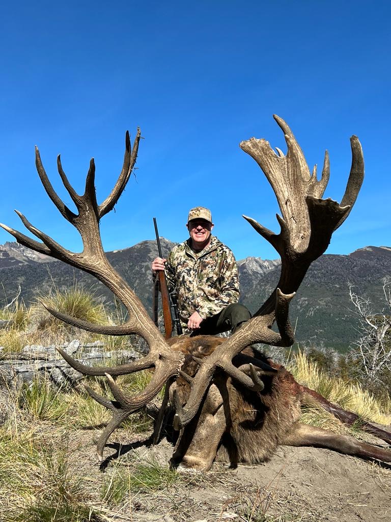 Hunter with a crowned red stag high above the Andes