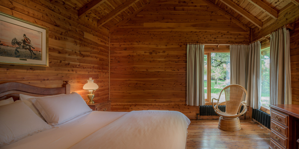 Cabin bedroom in cedar with windows onto the garden
