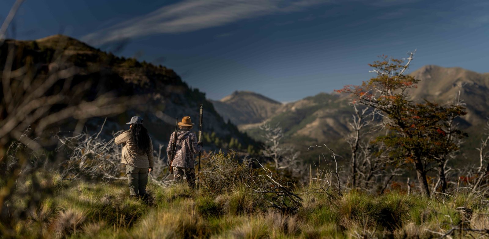 Hunter and guide glassing across a Patagonian valley from an open ridge at Parque Diana