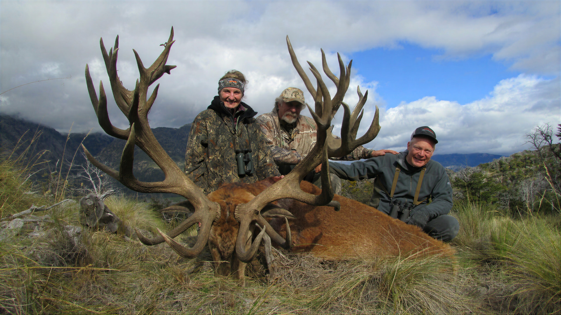 Three hunters behind an exceptional gold-medal Patagonian red stag on a high mountain meadow