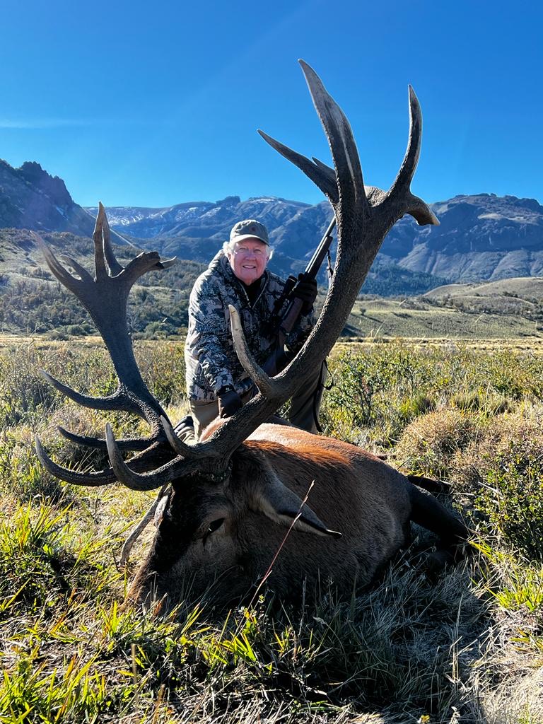 Hunter with a wide red stag on the open Patagonian steppe